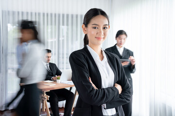 Portrait of happy young asian businesswoman looking at camera with motion blur background of...
