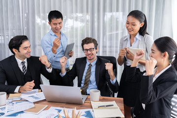 Group of happy businesspeople in celebratory gesture and successful efficient teamwork. Diverse race office worker celebrate after made progress on marketing planning in corporate office. Meticulous