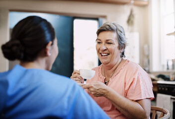 Retirement, caregiver and happy woman in kitchen for support, kindness and healthcare. Tea, talking and medical worker or nurse with senior female person in home for conversation, advice or chat