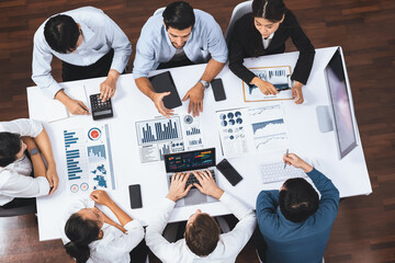 Top view analyst team utilizing BI Fintech to analyze financial data at table in meeting room. Analytic BI dashboard power on paper for business insight and strategic marketing planning. Prudent