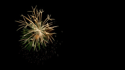 Time-lapse color photo of green and white fireworks exploding against a black night sky with copy...