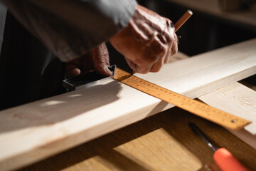 Close-up of carpenter taking measurement of a wooden plank in his workshop