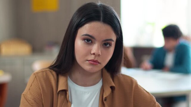 Portrait indoors sad upset serious frustrated Caucasian pupil teen girl teenager student female teenage woman lady schoolgirl looking at camera in class education study school university problem class
