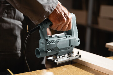 Carpentry work concept. Carpenter working on wood in workshop with wooden furniture. Carpenter use professional sawing tools