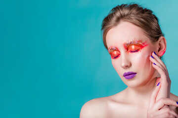 Tranquil Beauty with Bold Creative Makeup. Woman with closed eyes and vibrant makeup, purple lips, posing peacefully with hands near face.