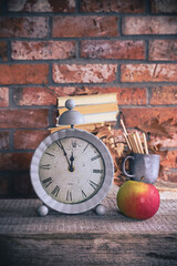 Back to school - clock, books and school supplies on bricks background