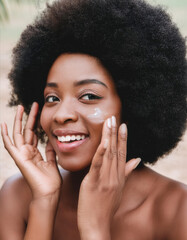 Smiling African American female putting cream on face