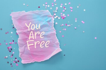 Inspirational "You Are Free" Message on Torn Paper with Butterfly Confetti on Blue Background