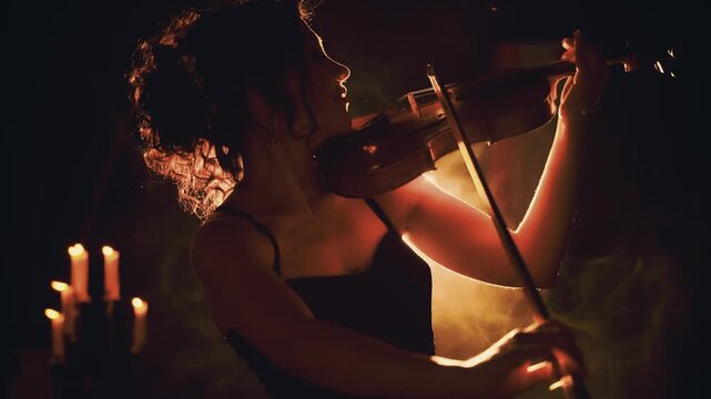 fantasy woman violinist playing the violin classic style. Girl musician hands in motion art music artist on stage. Black silhouette dark room full smoke magic light red orange flare. beauty sexy lady
