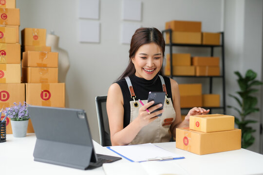 Asian sme business woman is working in her home office, using her smartphone to check a customer order on an online marketplace