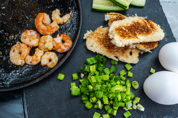 Fried shrimp on the table with warmed bread toast, green onions and eggs. Delicious and healthy food. Selected Focus