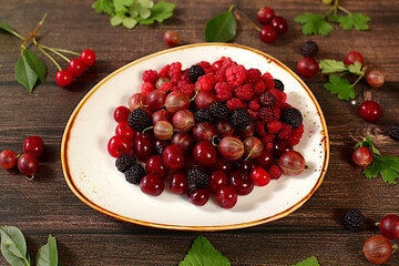 Summer fresh berries, cherries, blackberries, gooseberries and raspberries on a wooden background with leaves, banner for shops, rustic harvest, healthy natural food concept,