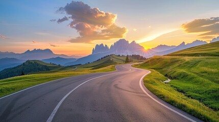Winding Road Through Green Hills at Sunset With Mountain Peaks in the Background