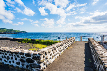 Obraz premium Coastal promenade along Almoxarife beach with azure ocean water, Faial island, Azores, Portugal