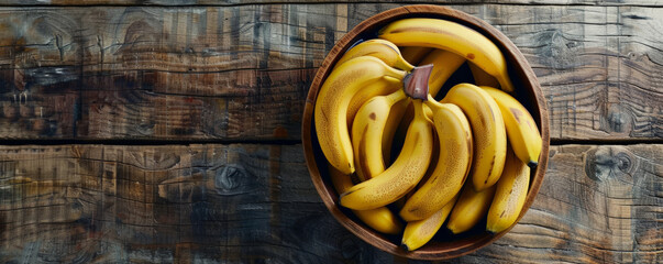 A wooden basket filled with fresh organic bananas, top-down view, with text space on a rustic wooden table background.
