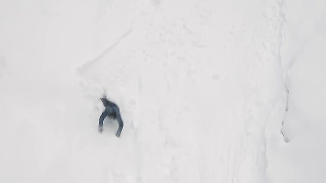 snowboarder rolling down mountainside falls into snowdrift, slow motion