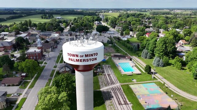 the Water Tower of Minto Palmerston with houses, road and green fields on a sunny day