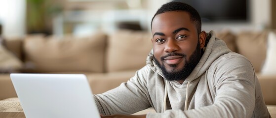 Obraz premium A young man with a beard smiles while using a laptop at home