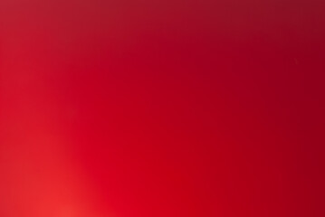 Blurry bright red background of the painted metal surface.