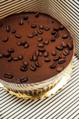 gourmet store bought tiramisu cake with coffee bean garnish, in black and white striped box