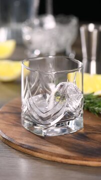 Preparing a cool cocktail Gin with tonic, lemon and rosemary. Vertical video, real time.