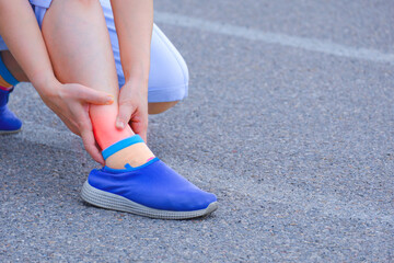 Adult woman hand holding ankle on the running track after injuring her ankle during jogging at sport field 