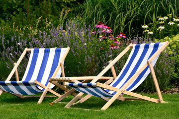 leżaki w biało-niebieskie pasy w ogrodzie, leżaki w ogrodzie, kącik wypoczynkowy z leżakiami, blue and white striped deckchairs in the garden, deckchairs in the garden, empty deck chairs 