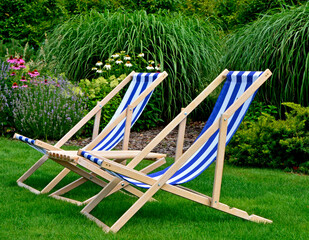 leżaki w biało-niebieskie pasy w ogrodzie, leżaki w ogrodzie, kącik wypoczynkowy z leżakiami, blue and white striped deckchairs in the garden, deckchairs in the garden, empty deck chairs, seating area © kateej