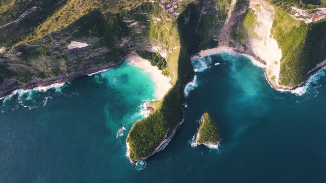Stunning aerial shot of Kelingking Beach in Nusa Penida, Bali, featuring its iconic cliff formation and pristine turquoise waters. A popular tourist destination known for its dramatic landscape.