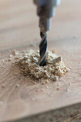 Close-up of a drill bit boring into wood, creating sawdust