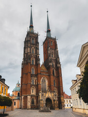 Obraz premium Front view of a Gothic cathedral in Wroclaw, Poland, showcasing intricate architectural details and historical significance under a cloudy sky.