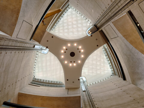 Interior view of a modern atrium with a geometric ceiling and concrete walls, emphasizing innovative architecture and contemporary design.
