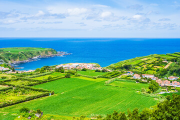 View of ocean, green farming fields and hills with flowers on north eastern coast of Sao Miguel island, Azores, Portugal