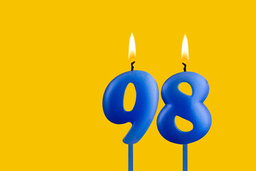 Blue birthday candle on yellow background - Number 98