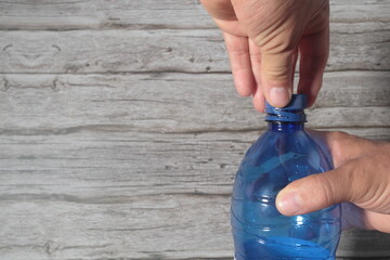 mano sobre tapon botella abriendo cerrando azul