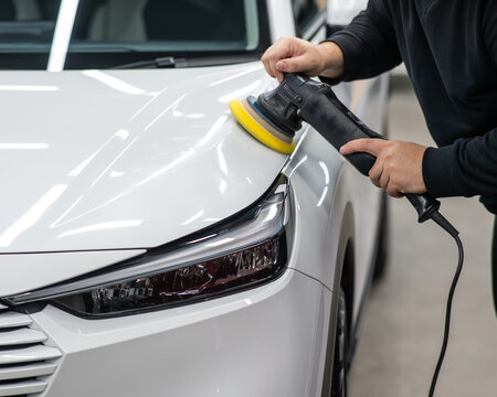 Process of polishing white car hood surface using orbital polishing machine. 