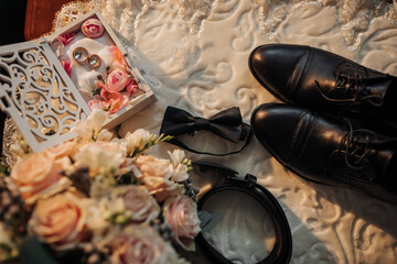 A pair of brown shoes with a pocket watch and a wedding ring on them. The watch is set at 12:00