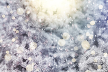 Sunlit decorated Christmas tree in a snowy winter forest, with falling snow and a soft, blurred background.
