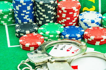 Handcuffs and a gun on a poker table - casino crime concept, underground casinos. illegal games, gambling concept. set of playing cards with dices, money and chips, on table. Casino concept, games.