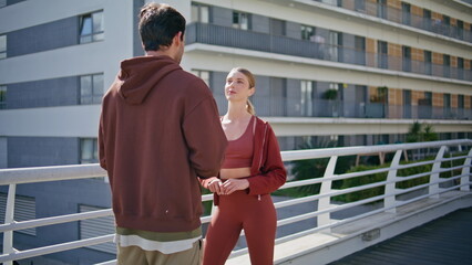 Relaxed athletes resting together on city street. Smiling woman enjoying chat