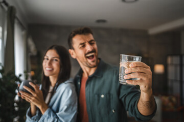 Portrait of couple stand with coffee and water, watch intro the window