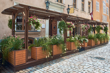 Summer street in the old town of Riga, Latvia. Wooden boxes with beautiful flowers outside a cafe.