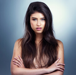 Naklejka premium Portrait, hair care and woman with wellness, arms crossed and shine on blue studio background. Face, person and model with grooming routine, salon treatment and luxury with shampoo and dermatology