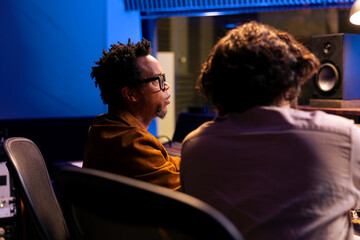 Team of musician and producer working on composing a song together, does mixing and mastering with...