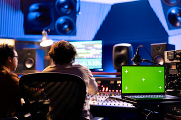 Artist and technician processing new sounds in professional studio and using audio console to edit...