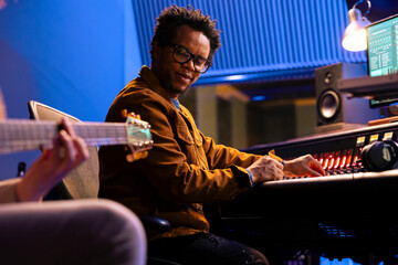 Musician creating a new hit song with guitar in control room, recording electro acoustic instrument...