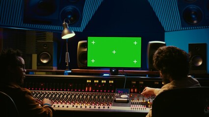 Team of music engineer and artist recording tracks on greenscreen, processing sounds to create a...