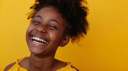 A cute black girl laughs sincerely against a yellow background, her face glowing with joy. It can be used for diversity, empowerment, and happiness concepts.