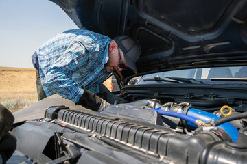 Blue pickup truck breaks down on the shoulder of a freeway while owner tries to assess the problem.