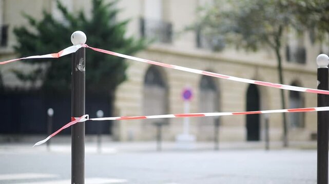 Red and white striped plastic tape in Paris, France. Boundary used to close off areas and streets. Parisian street closed for pedestrians.